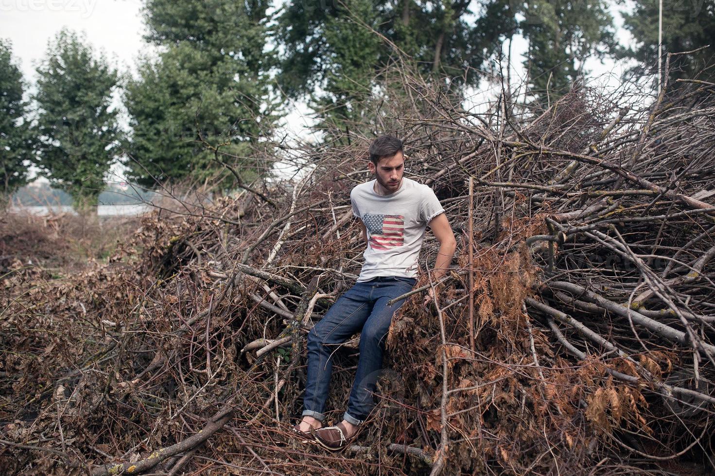 il uomo nel il autentico stivali e cimosa jeans su un' il sfondo di rami foto