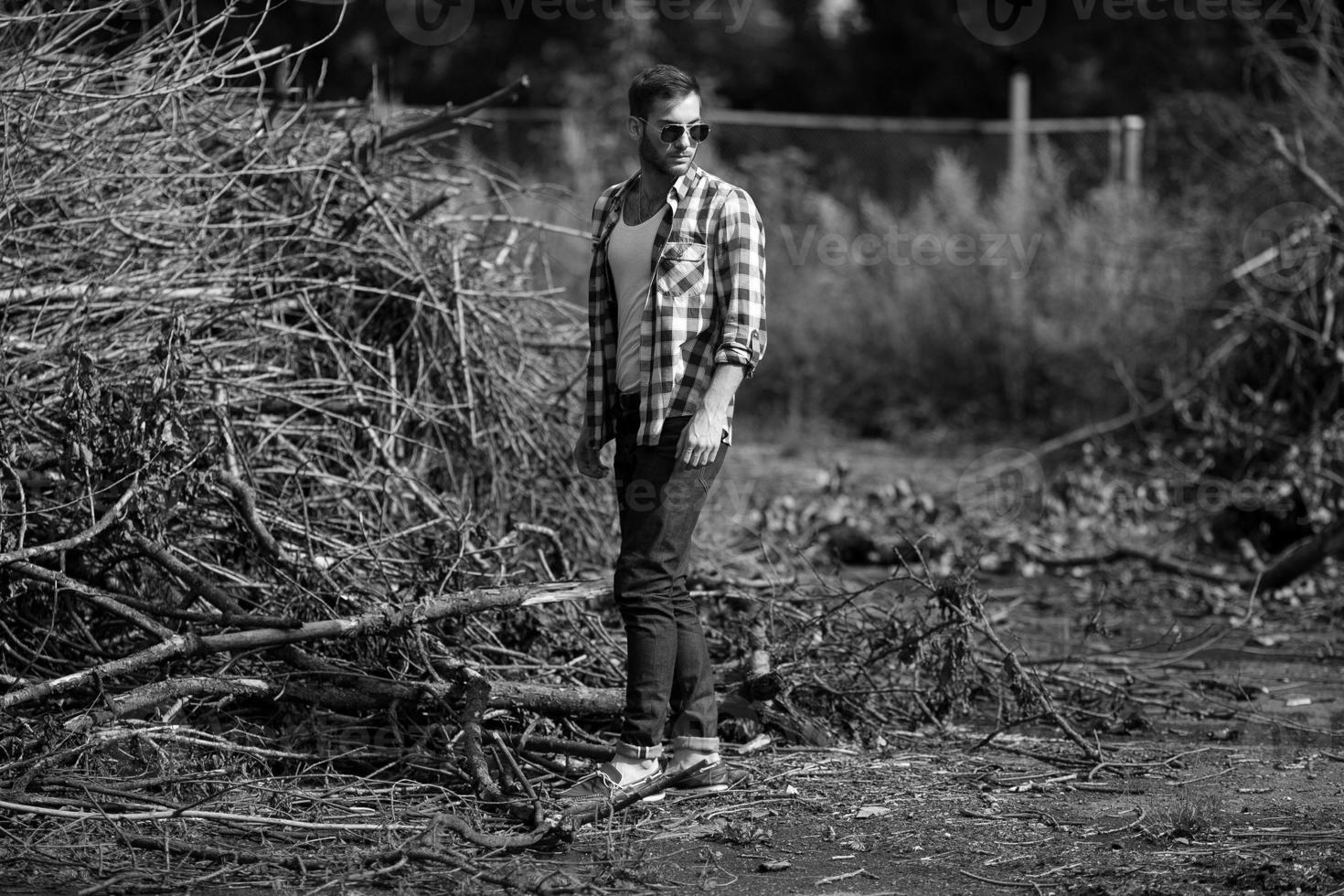 il uomo nel il autentico stivali e cimosa jeans su un' il sfondo di rami foto