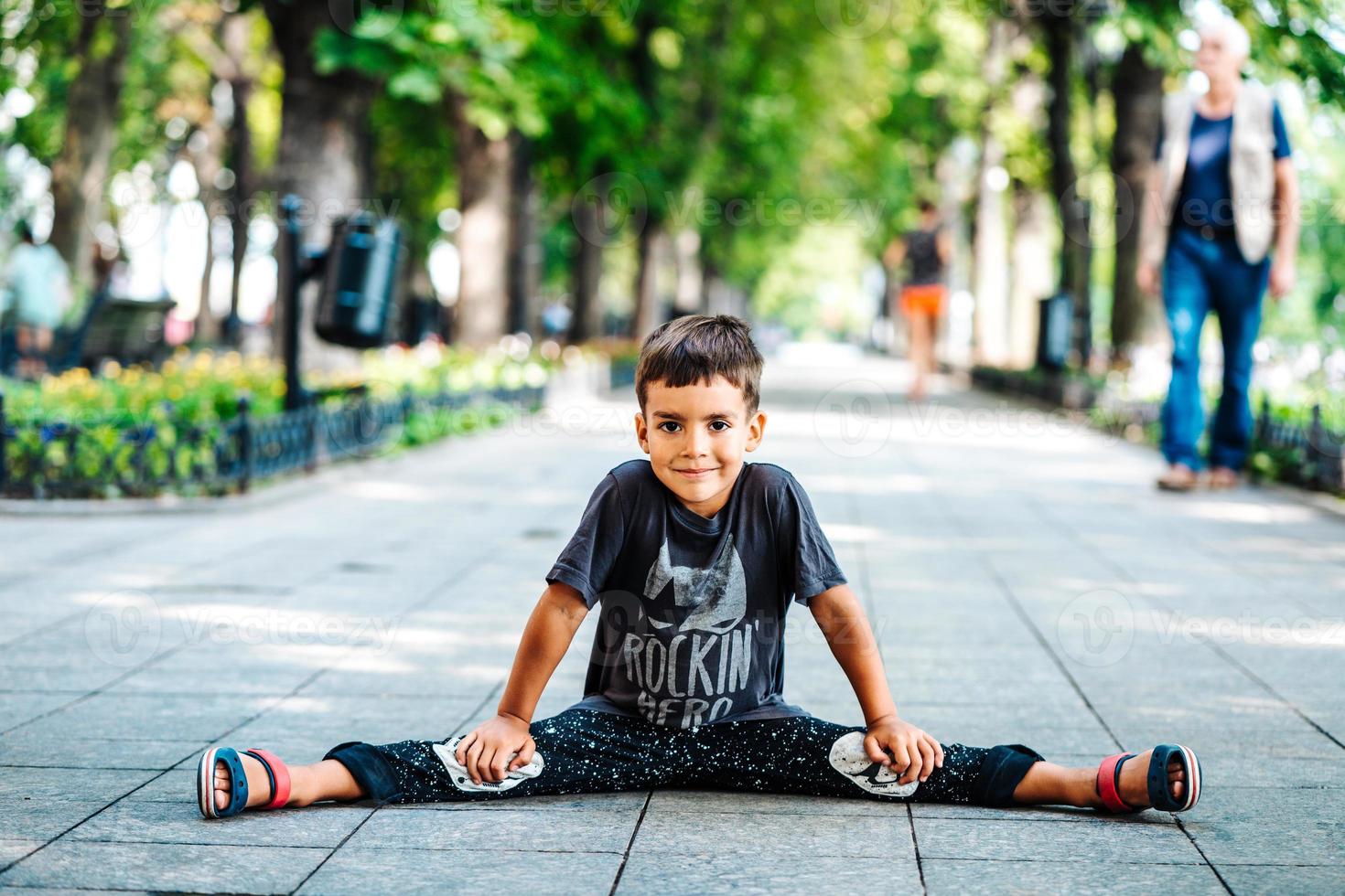 contento sorridente bambino ragazzo seduta su sentiero nel un' parco. foto