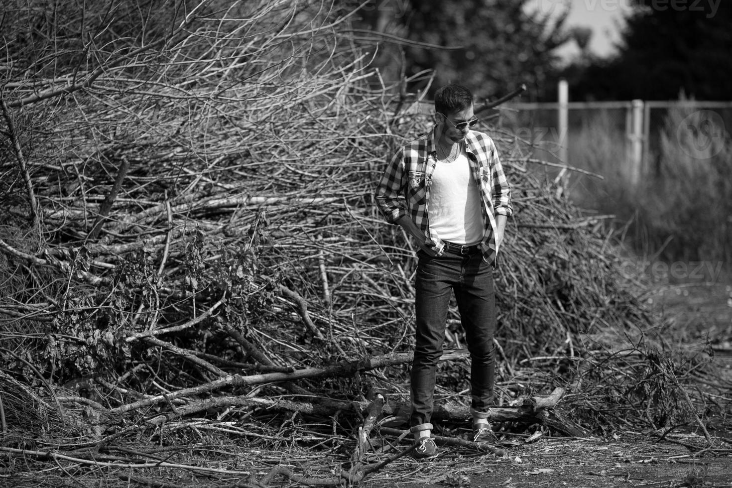 il uomo nel il autentico stivali e cimosa jeans su un' il sfondo di rami foto