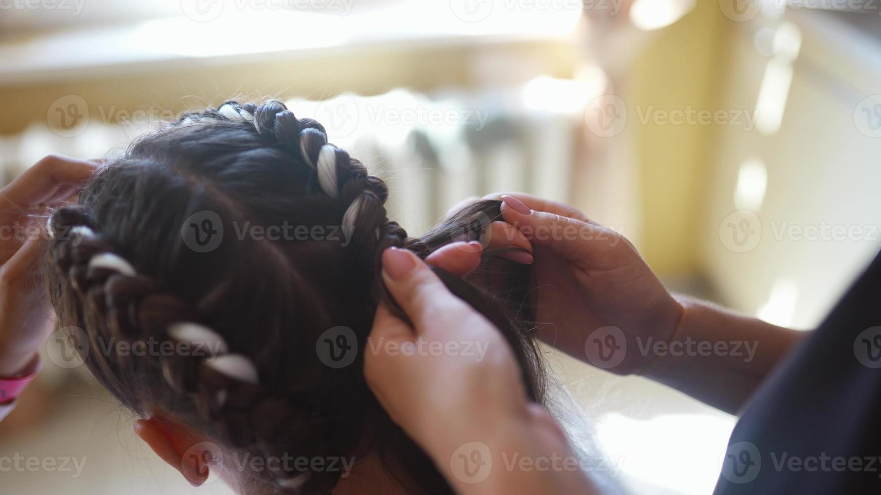 processi di intrecciare. maestro tesse trecce su testa nel un' bellezza salone, vicino su foto