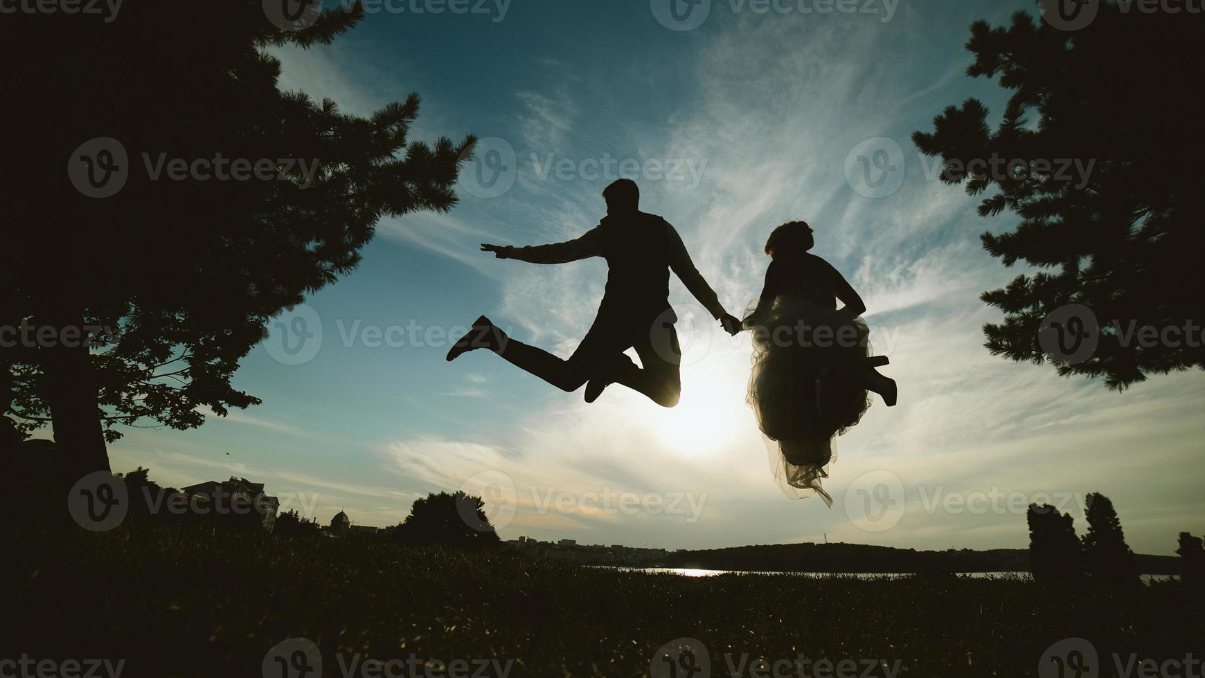 sposo e sposa salto contro il bellissimo cielo foto