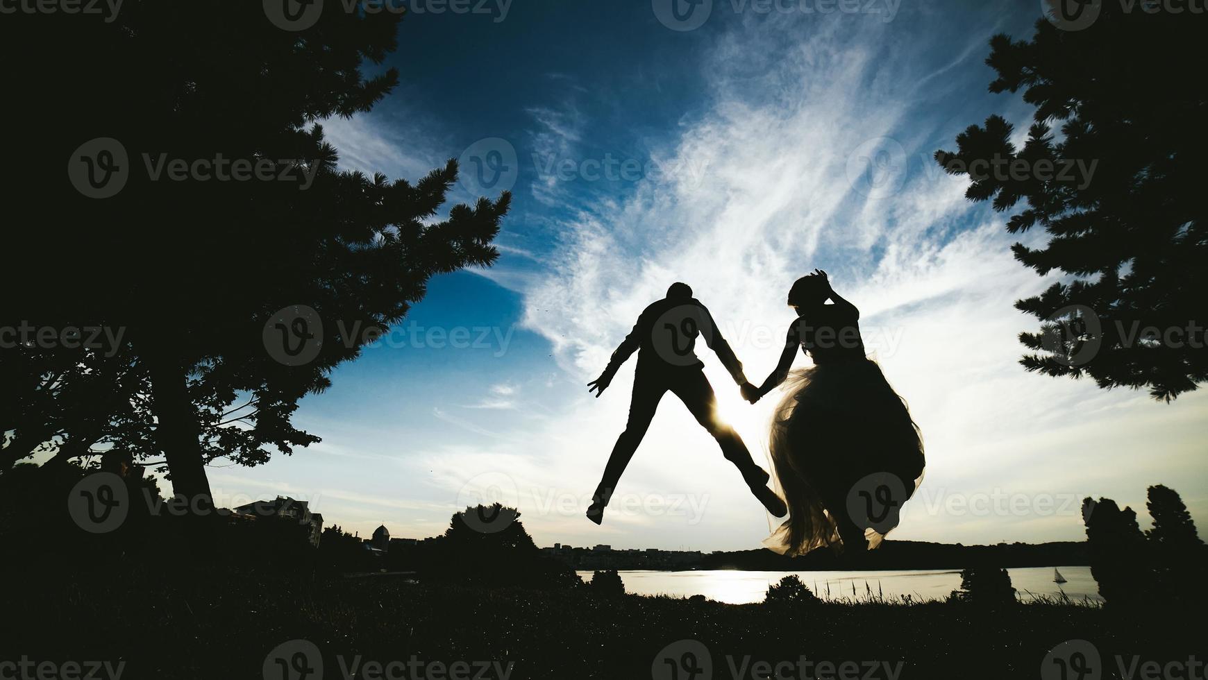 sposo e sposa salto contro il bellissimo cielo foto