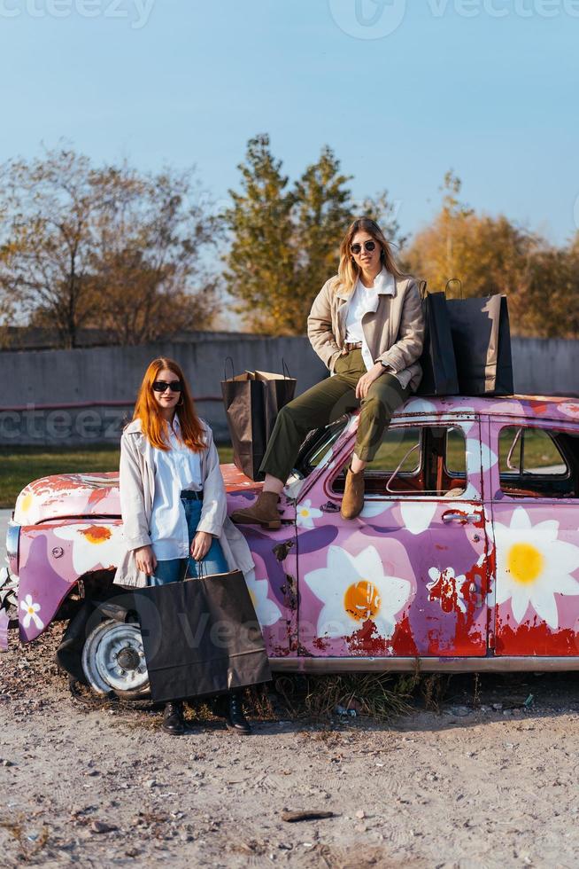 giovane donne in posa vicino un vecchio decorato auto foto