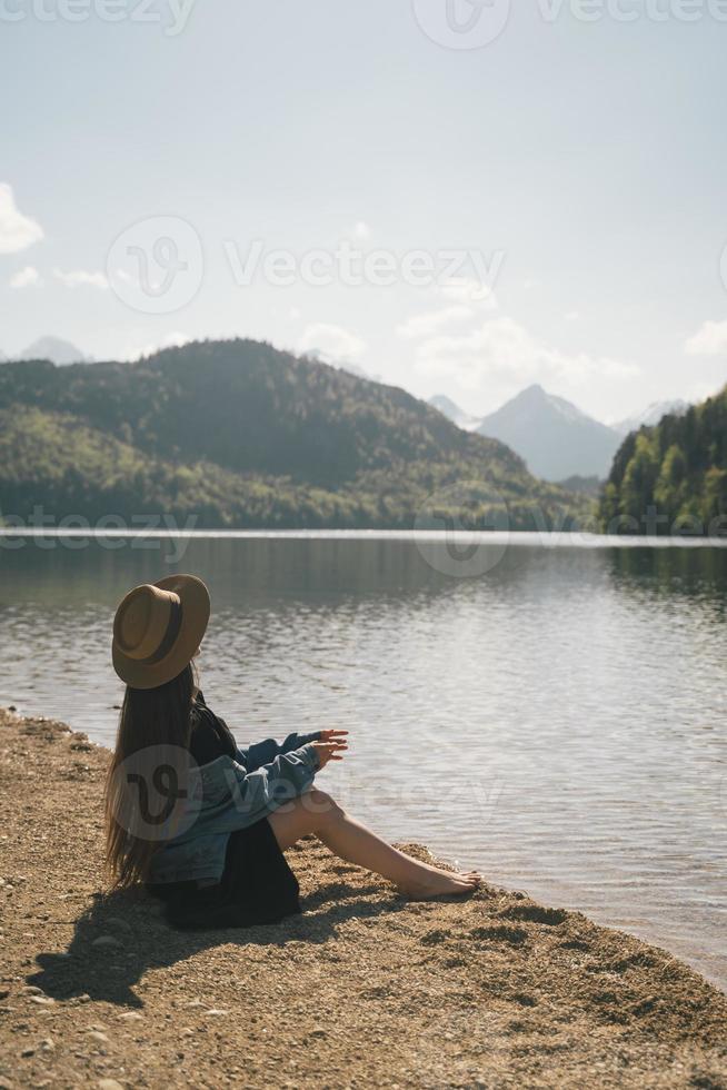 il ragazza nel il vestito e cappello di il lago nel il montagne foto
