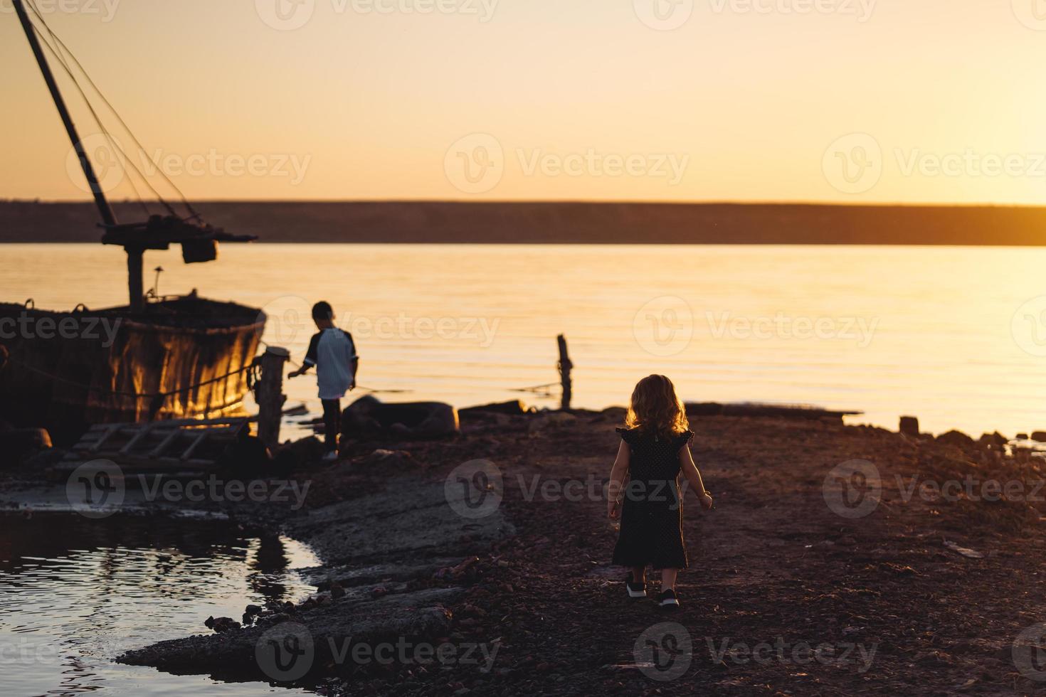 Due bambini camminare lungo il spiaggia, estate sera foto