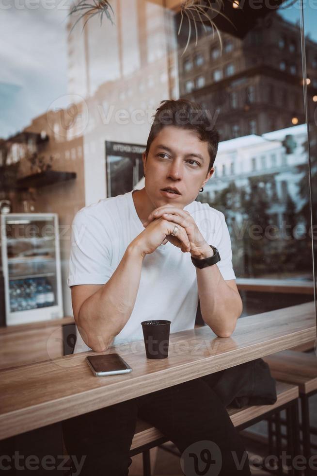 giovane, bello uomo è potabile il suo mattina caffè nel un' bar. foto