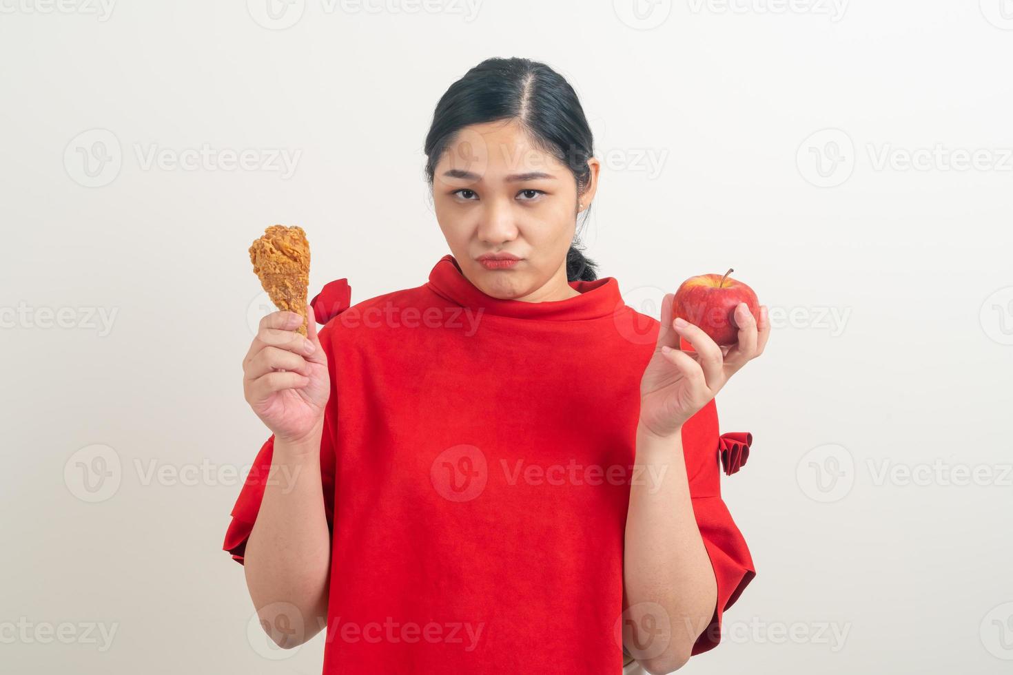donna asiatica con pollo fritto e mela a portata di mano foto