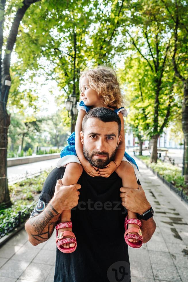 poco ragazza equitazione su papà collo foto