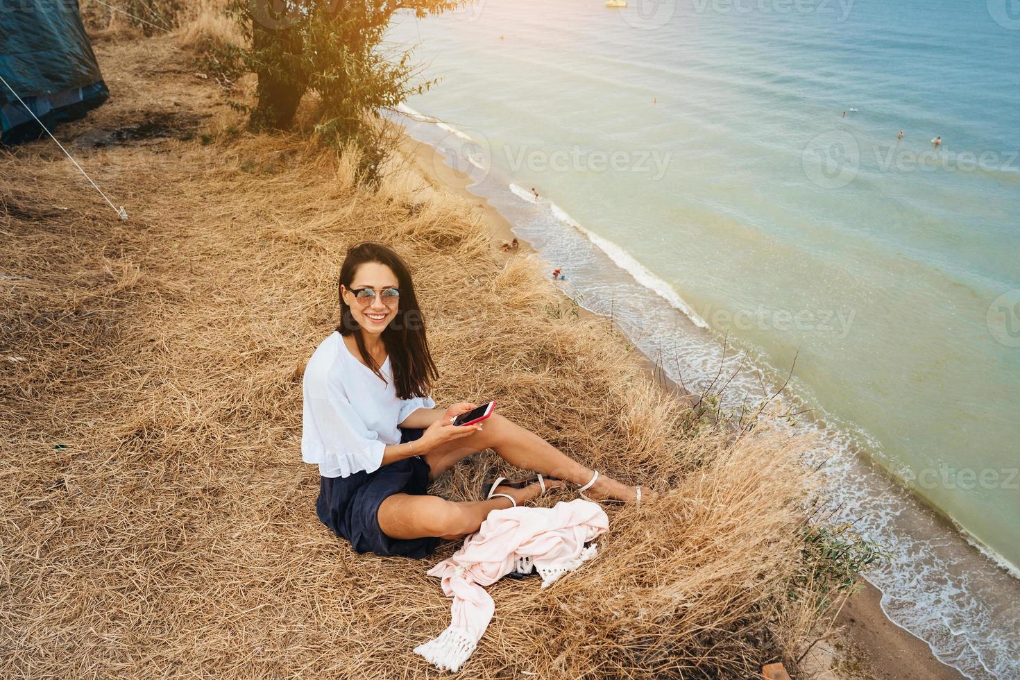 attraente donna nel estate gonna e camicia si siede su il riva foto