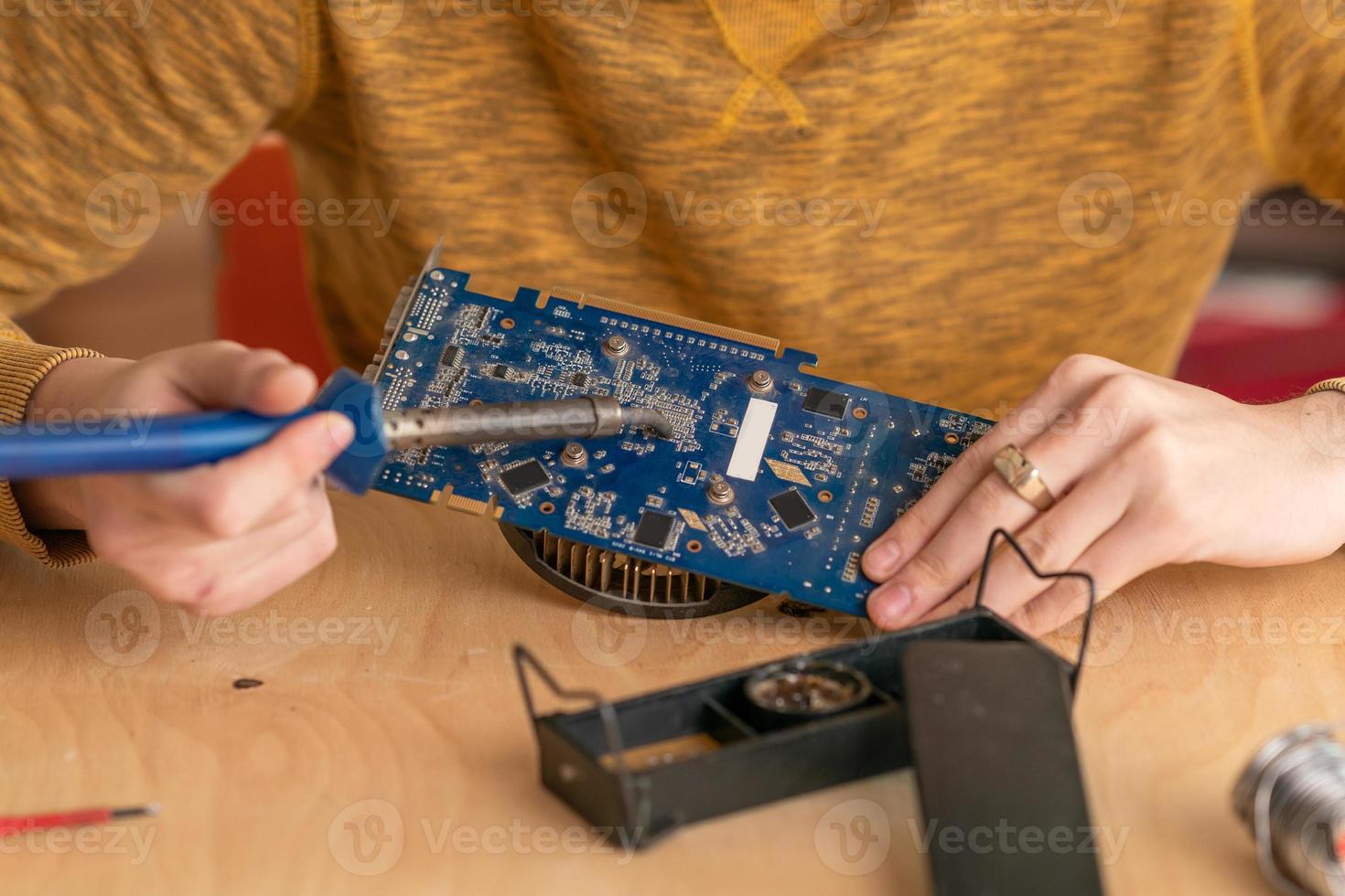 un giovane salda un microcircuito bruciato con un saldatore foto