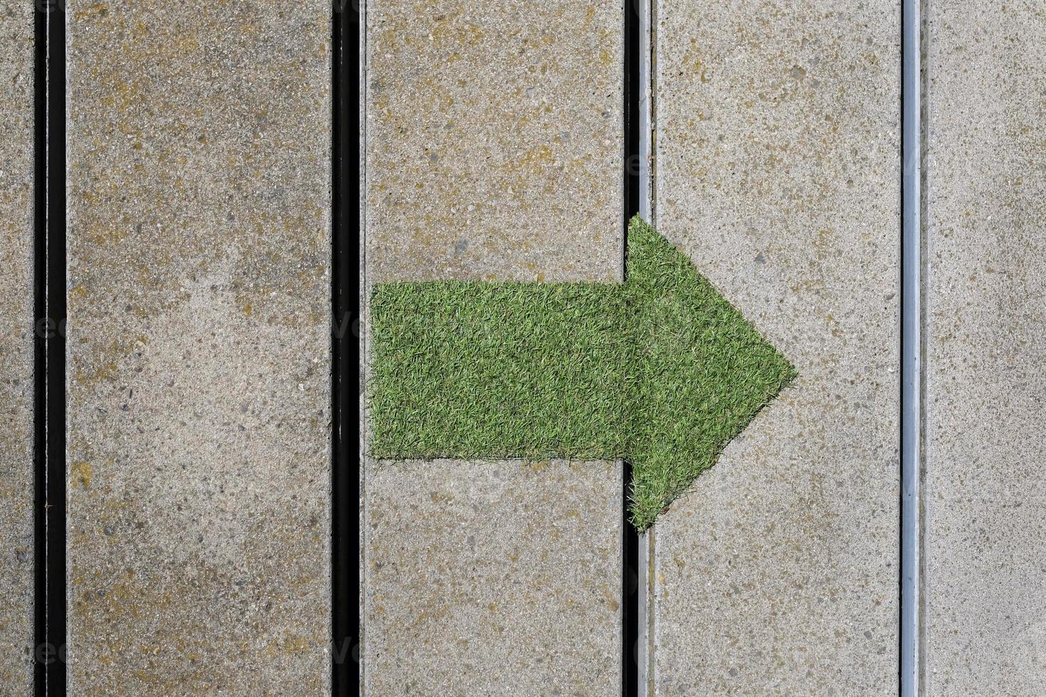 verde freccia fatto su di un' toppa di erba puntamento per il giusto foto