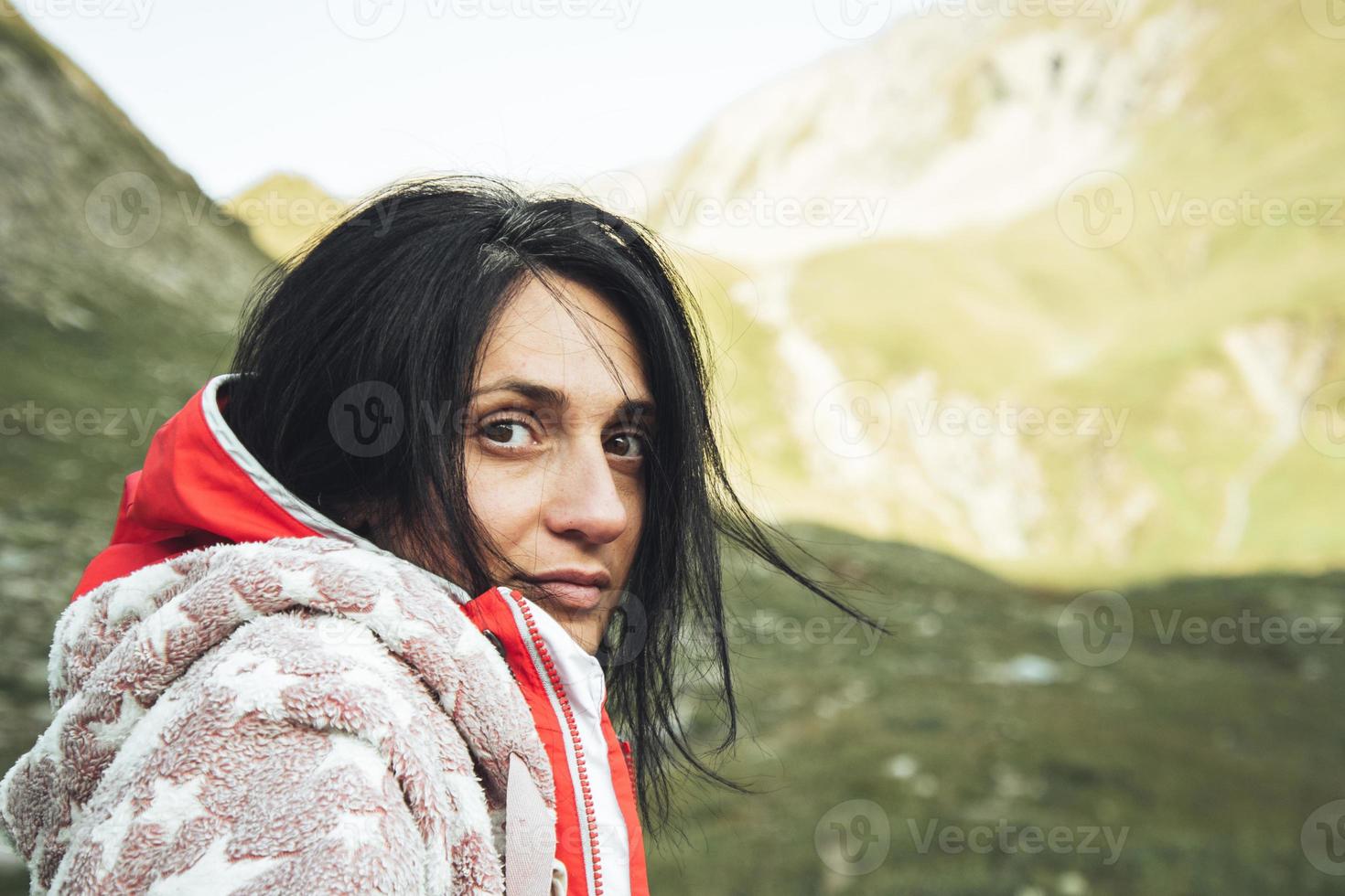 vicino su di caucasico donna viso guardare dritto con accogliente pigiama e blu addormentato Borsa su superiore nel natura con sole nel il sfondo. sfida e donna selvaggio campeggio concetto foto