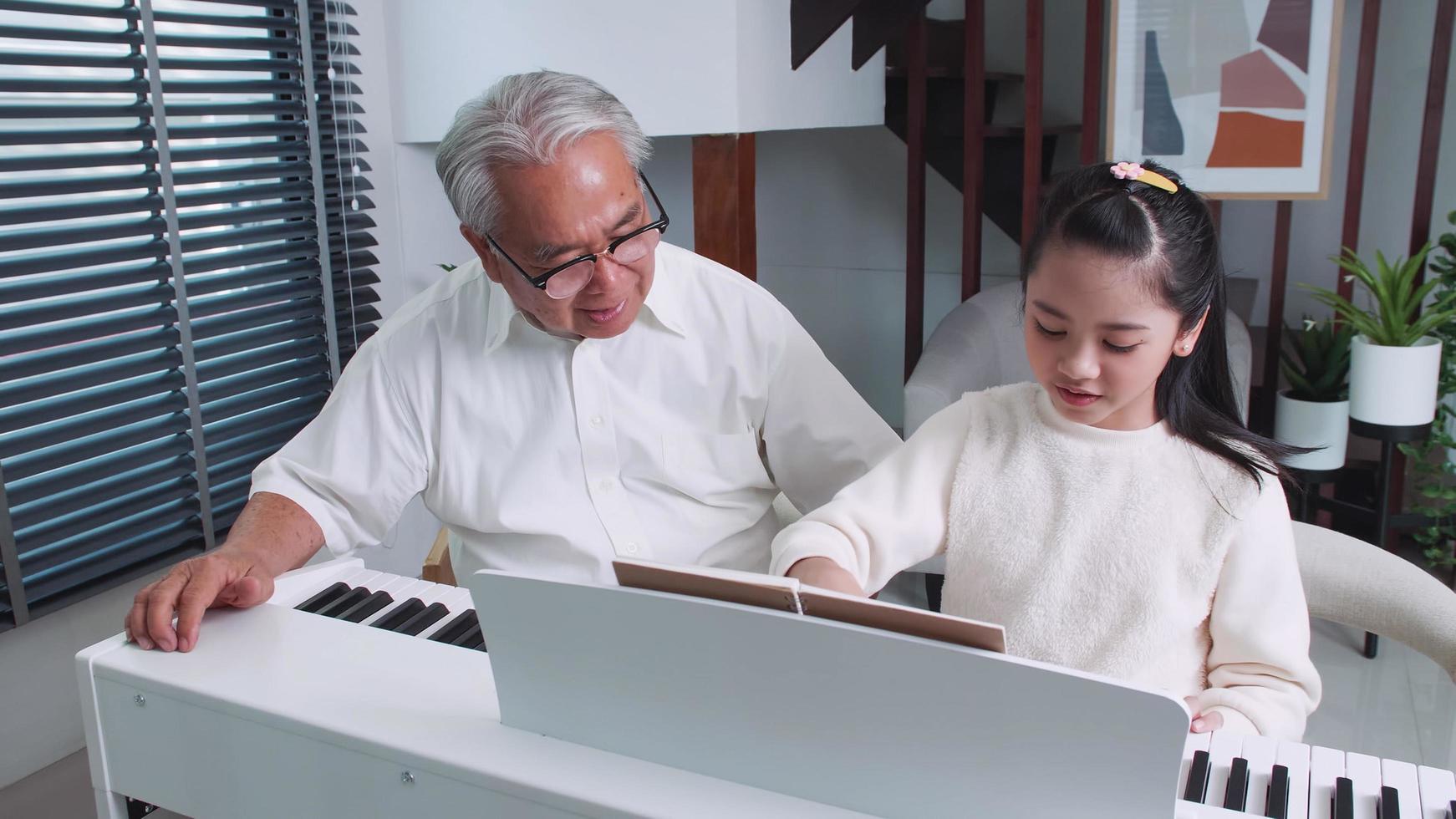 nonno è insegnamento poco nipotina per giocare il pianoforte a casa. foto