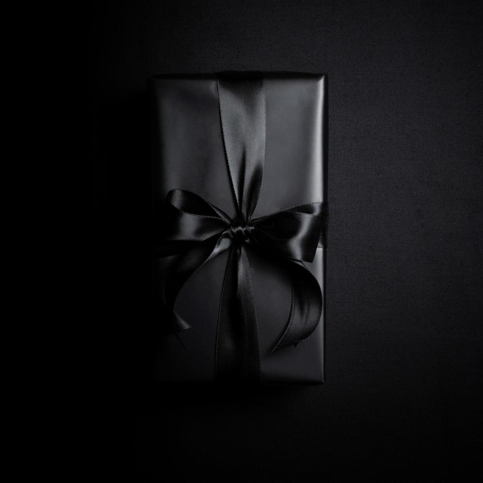 superiore Visualizza di nero regalo scatola con nero nastri isolato su nero sfondo. foto
