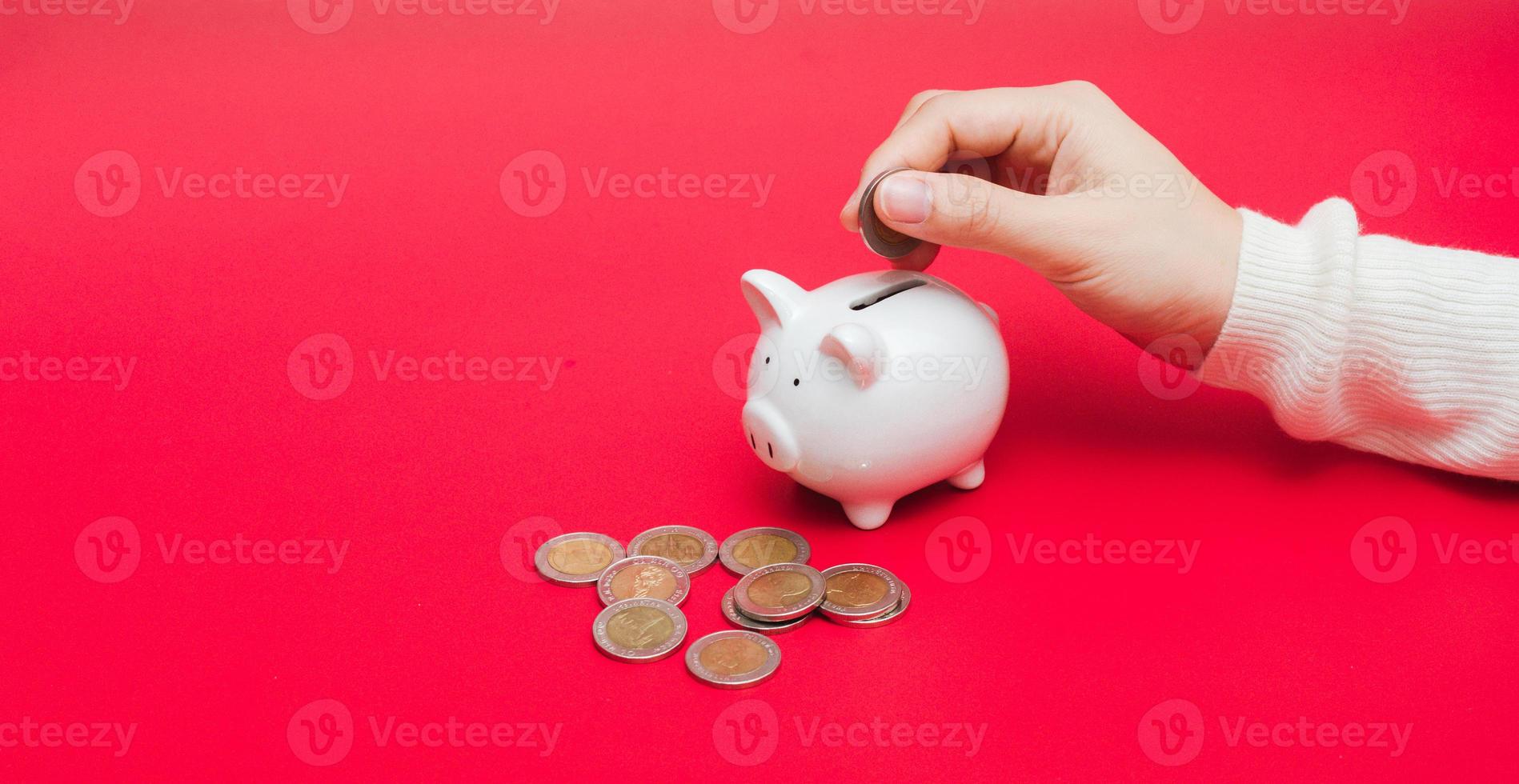 donna mano mettendo i soldi moneta in porcellino foto