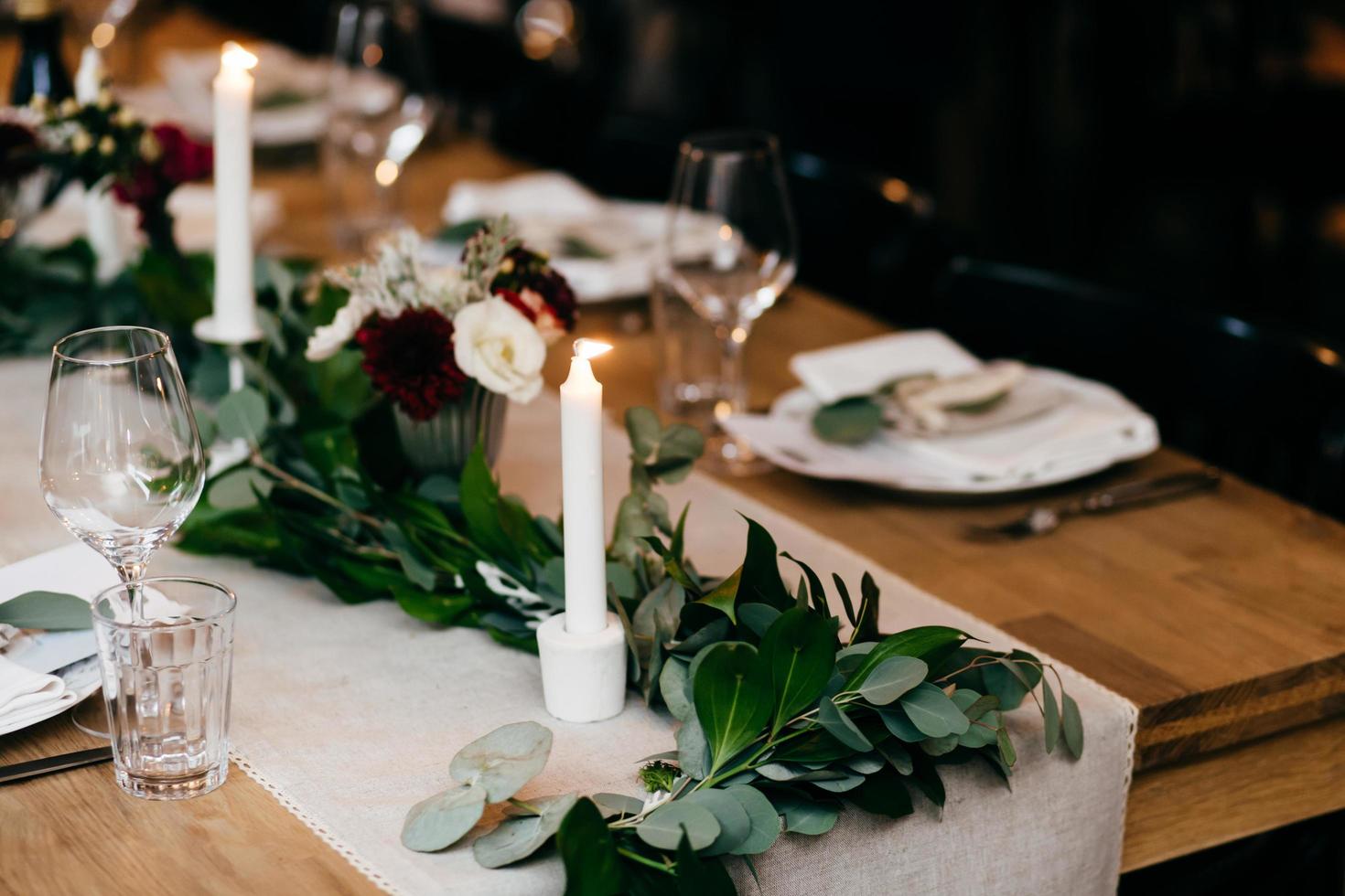 apparecchiare la tavola del banchetto. piatti, forchette, candele su tavola di legno con bella decorazione. posate e bicchieri da vino. ristorante interno accogliente. tavola servita per occasioni speciali. concetto di celebrazione foto