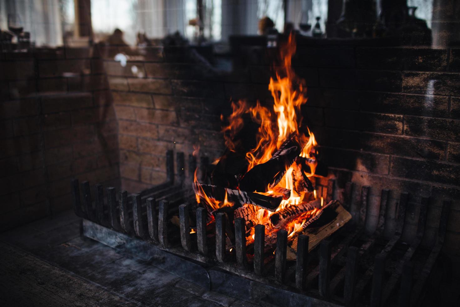 bellissimo luminosa fuoco fiamma. sfolgorante fuoco contro mattone parete sfondo. buio colori. ardente legna con Fumo. grande calore. ardente brace foto