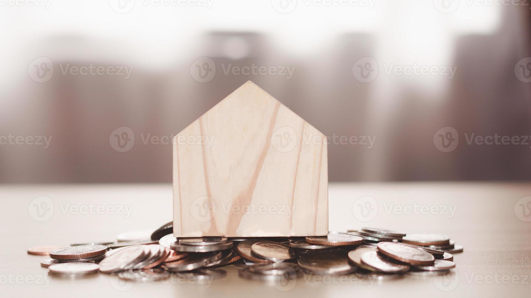 Salvataggio i soldi e finanziario obiettivi per un' famiglia concetto. il di legno casa su monete. prestito per vita, pianificazione per il futuro, vero tenuta investimento. foto