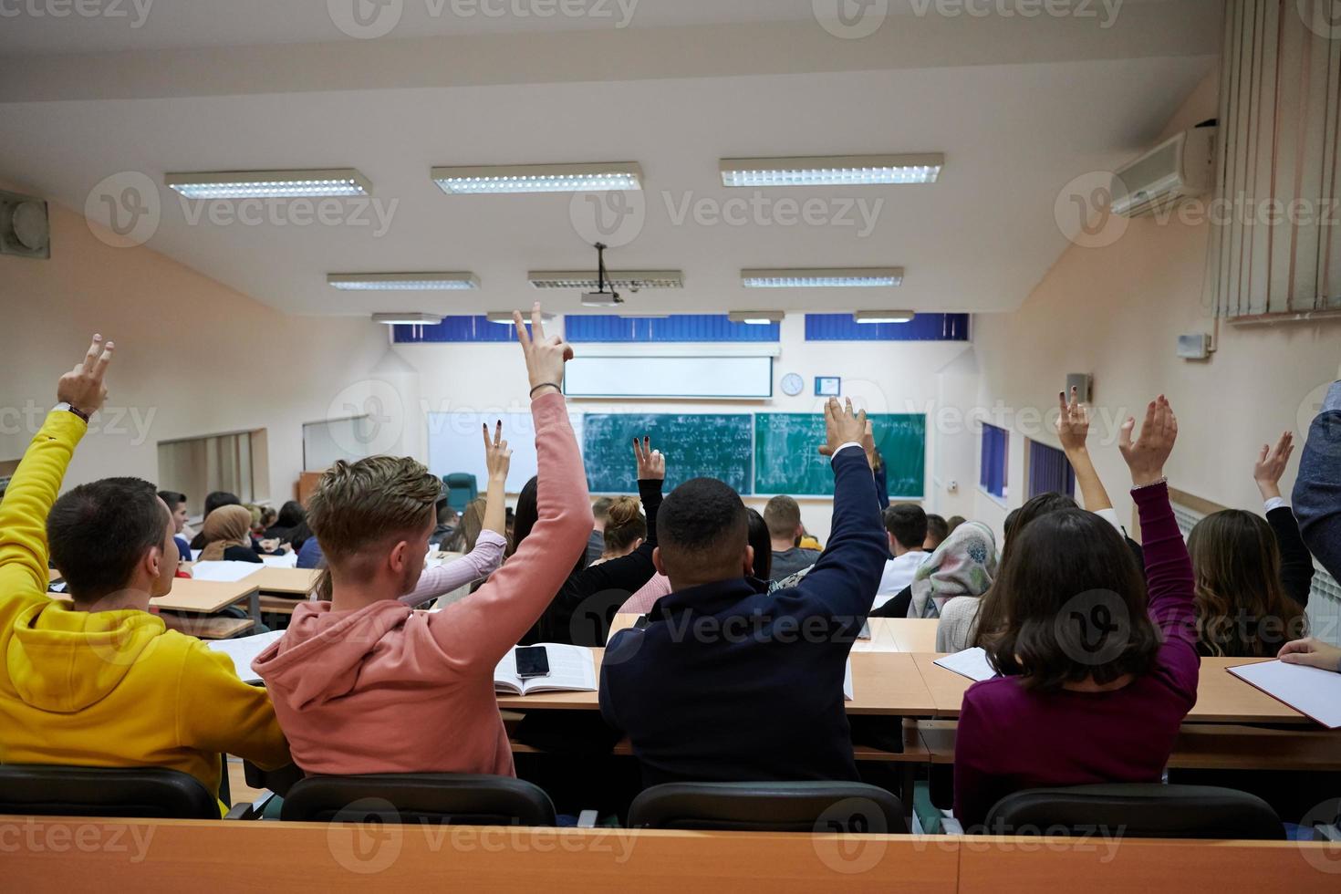 sollevato mani e braccia di grande gruppo di persone nel classe camera foto