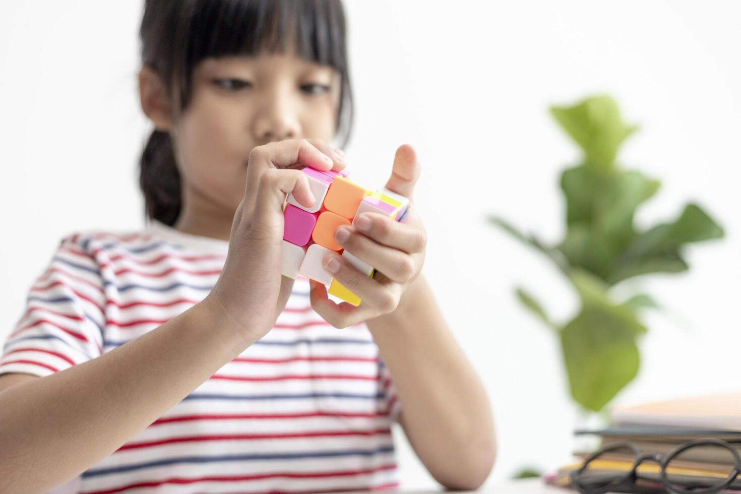 asiatico poco carino ragazza Tenere di rubik cubo nel sua mani. di rubik cubo è un' gioco quello aumenta il intelligenza di bambini. foto