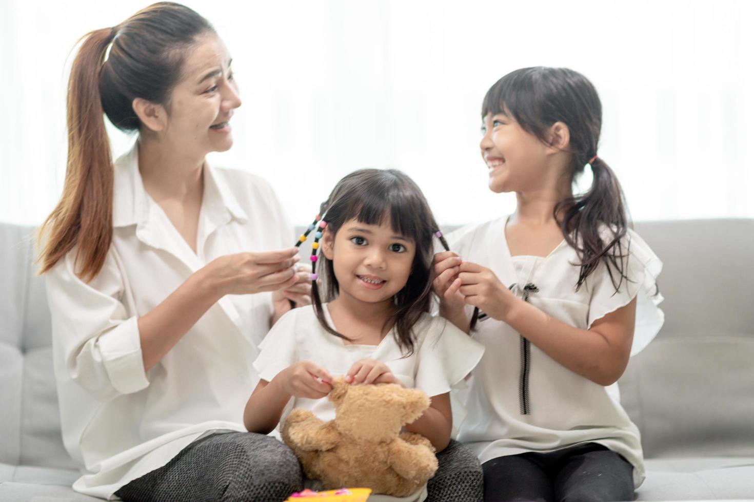 giovane madre asiatica che lega i capelli della figlia foto