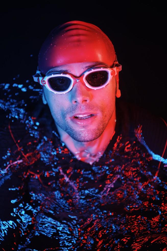 autentico triatleta nuotatore avendo un' rompere durante difficile formazione su notte neon gel leggero foto