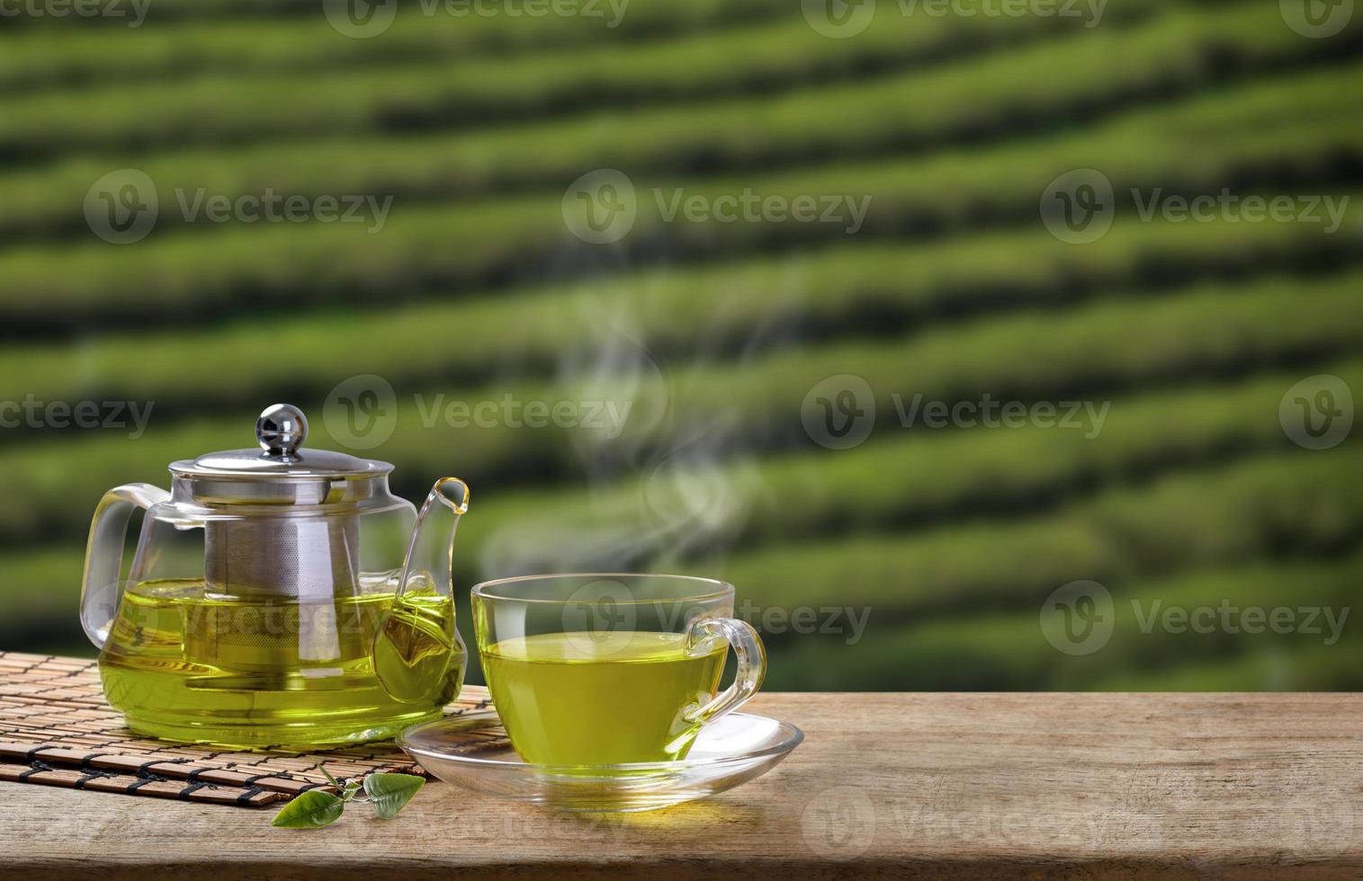 verde tè tazza e bicchiere brocche o barattoli. con e verde tè foglia licenziamento su il di legno tavolo e il tè piantagioni sfondo foto