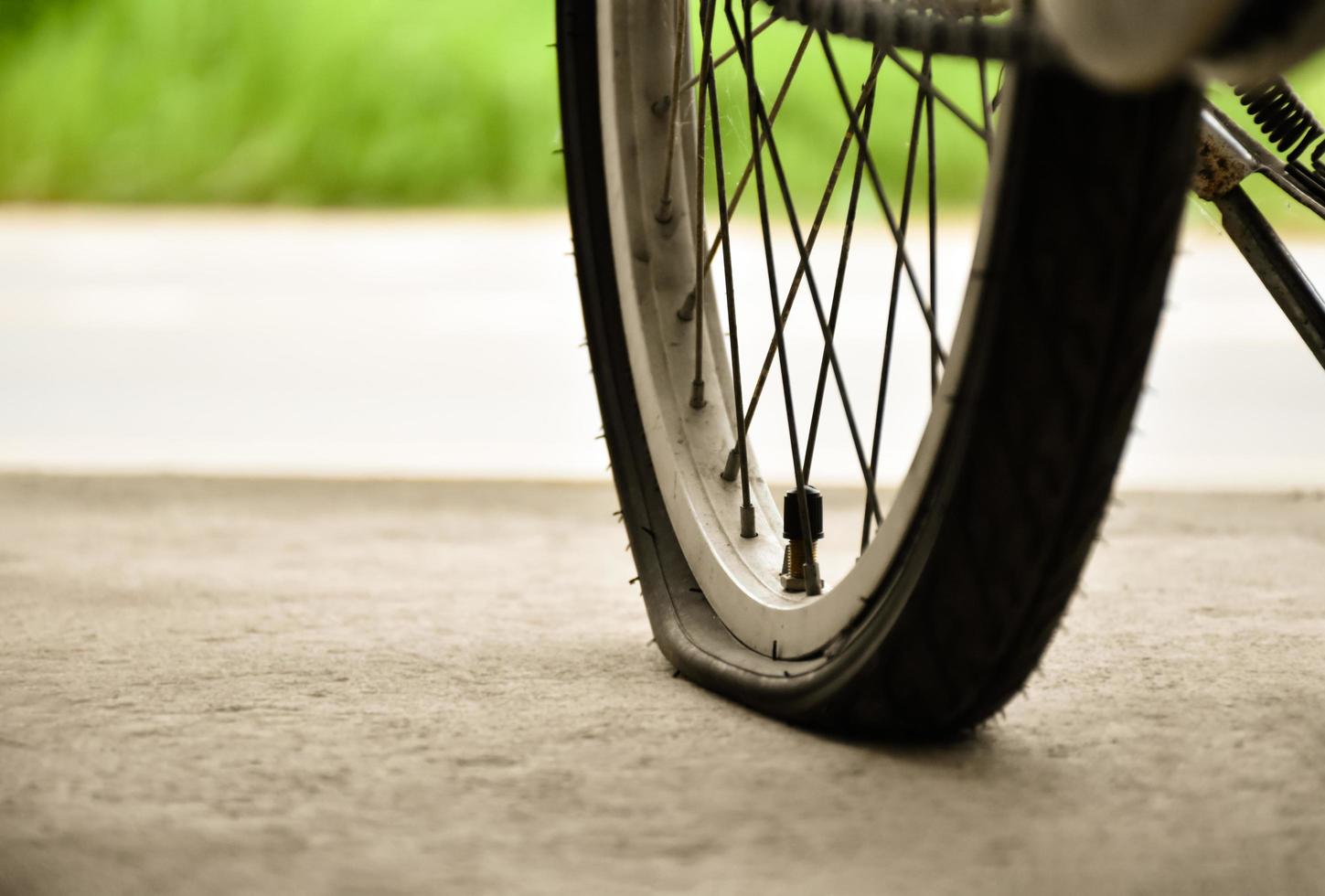 avvicinamento Visualizza di posteriore piatto pneumatico di Vintage ▾ bicicletta quale parcheggiata su marciapiede accanto il strada. morbido e selettivo messa a fuoco. foto