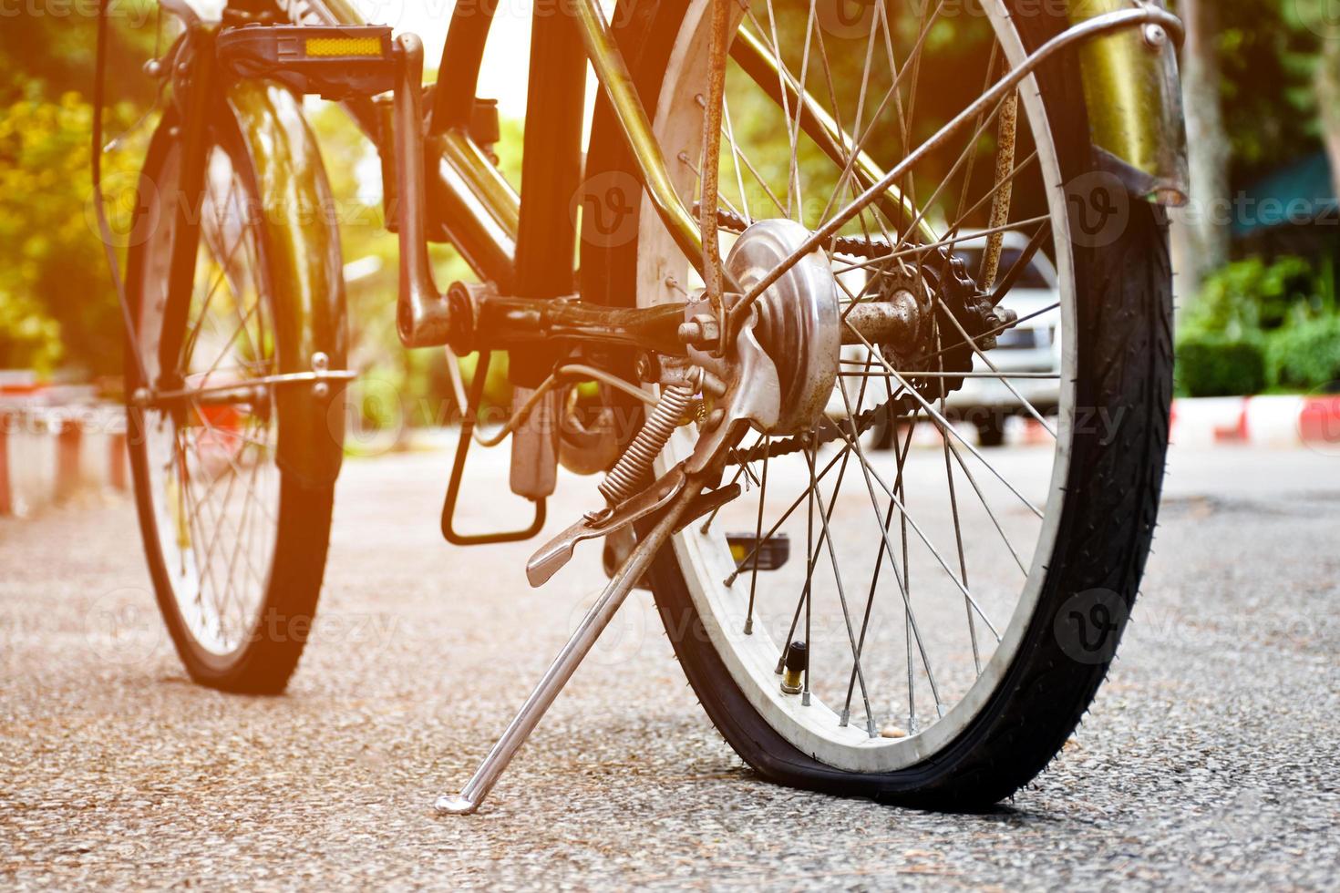 avvicinamento Visualizza di posteriore ruota di vecchio bicicletta quale è piatto e parcheggiata su marciapiede nel il pubblico parco, morbido e selettivo messa a fuoco. foto