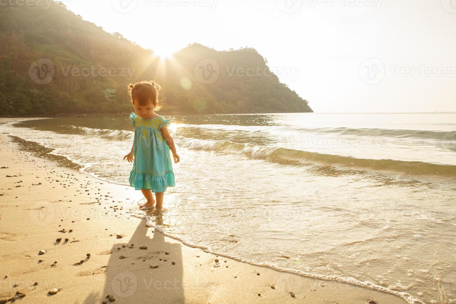 poco ragazza in esecuzione nel mare acqua su il spiaggia. foto