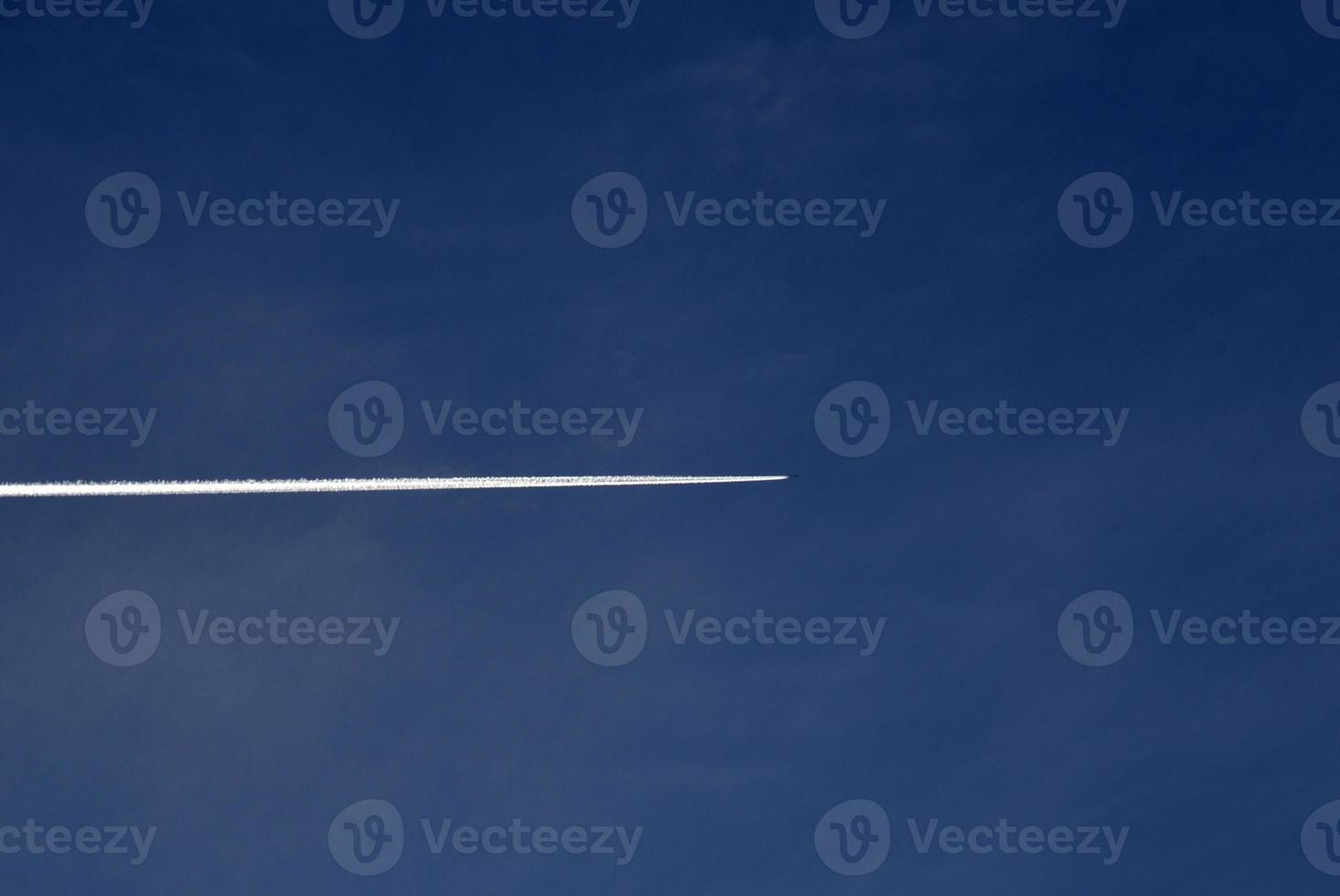 un' aereo volante nel il blu cielo e nuvole. un' bianca scia di condensazione a partire dal un aereo nel il estate cielo. foto