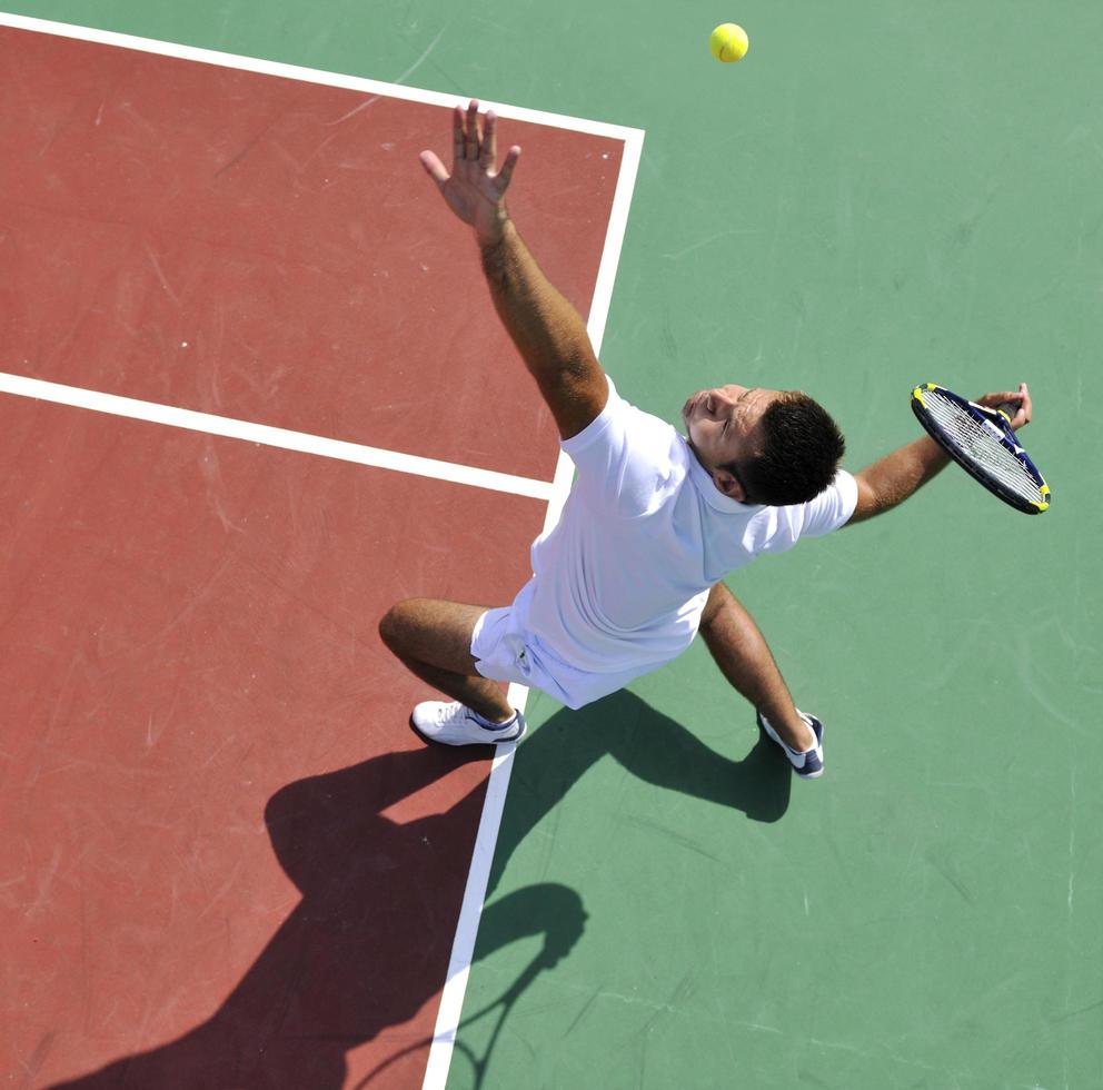 il giovane gioca a tennis all'aperto foto