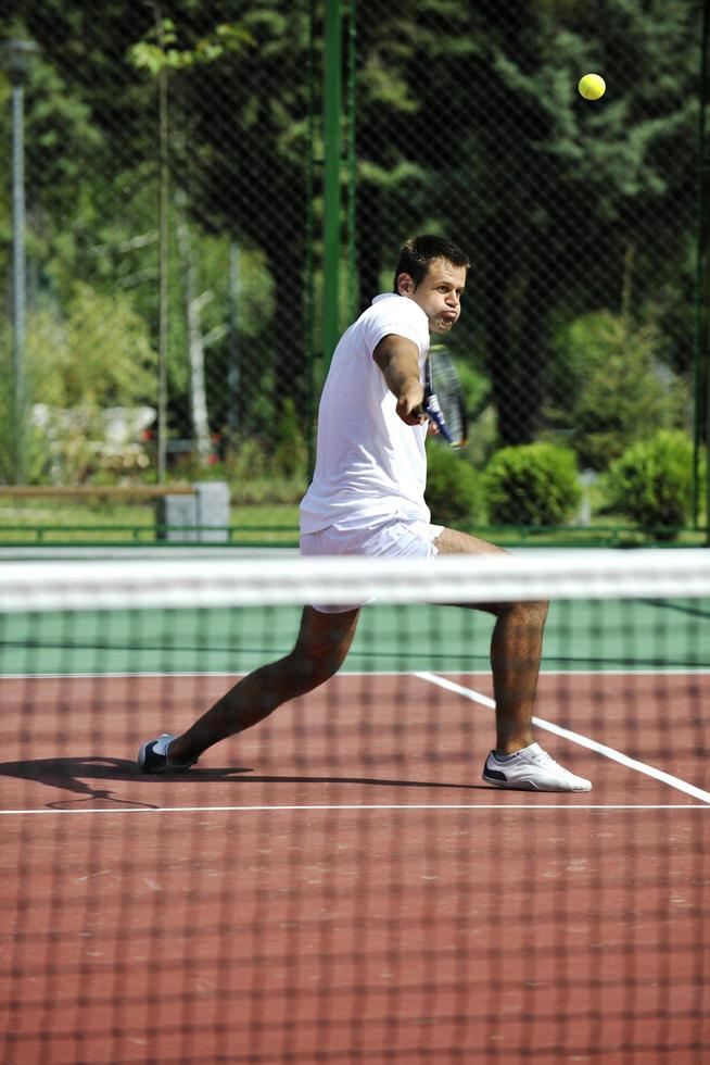 il giovane gioca a tennis all'aperto foto