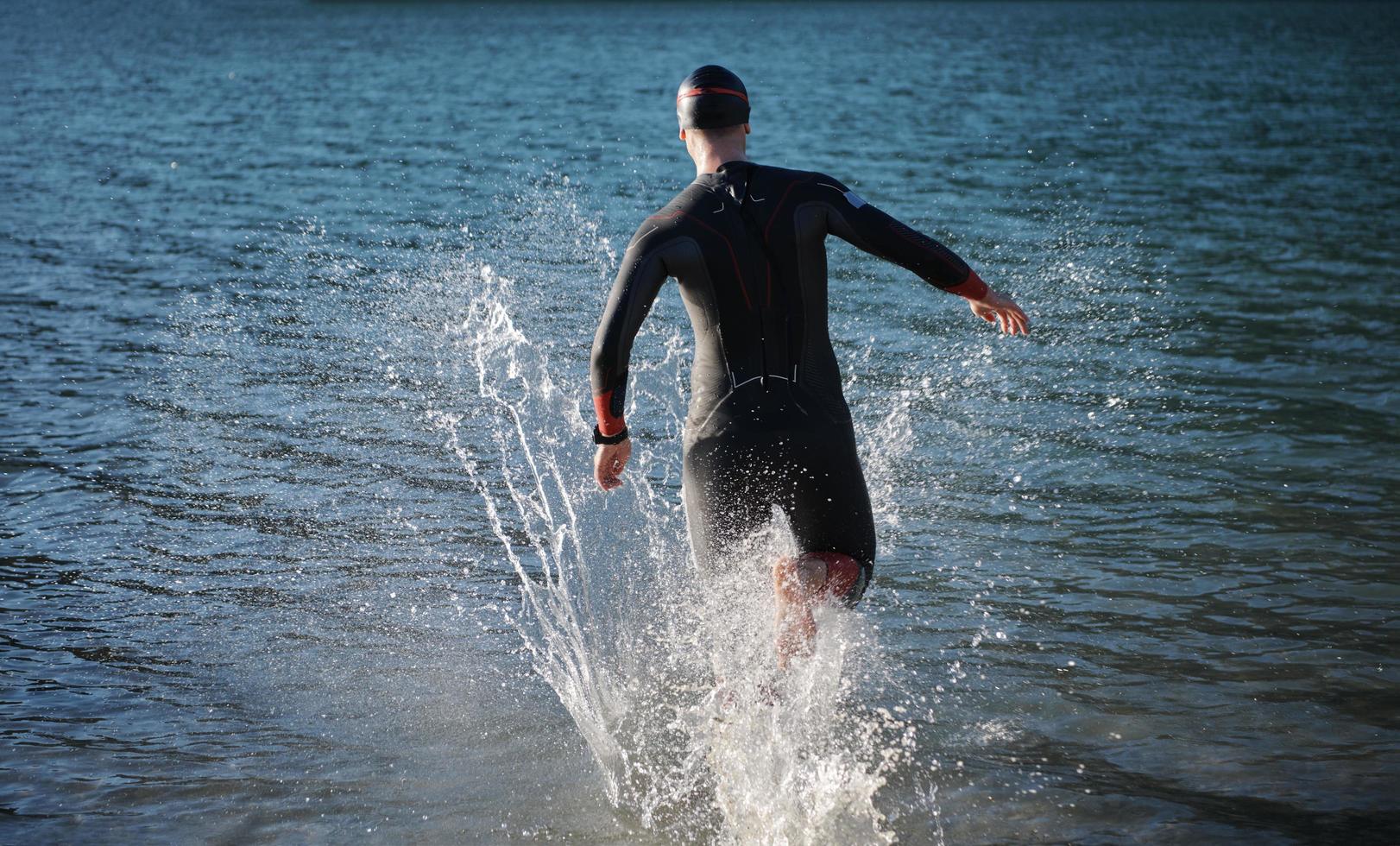 atleta di triathlon che inizia l'allenamento di nuoto sul lago foto