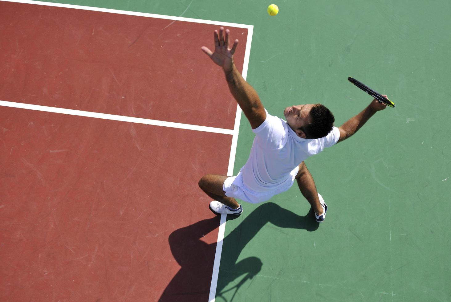 il giovane gioca a tennis all'aperto foto