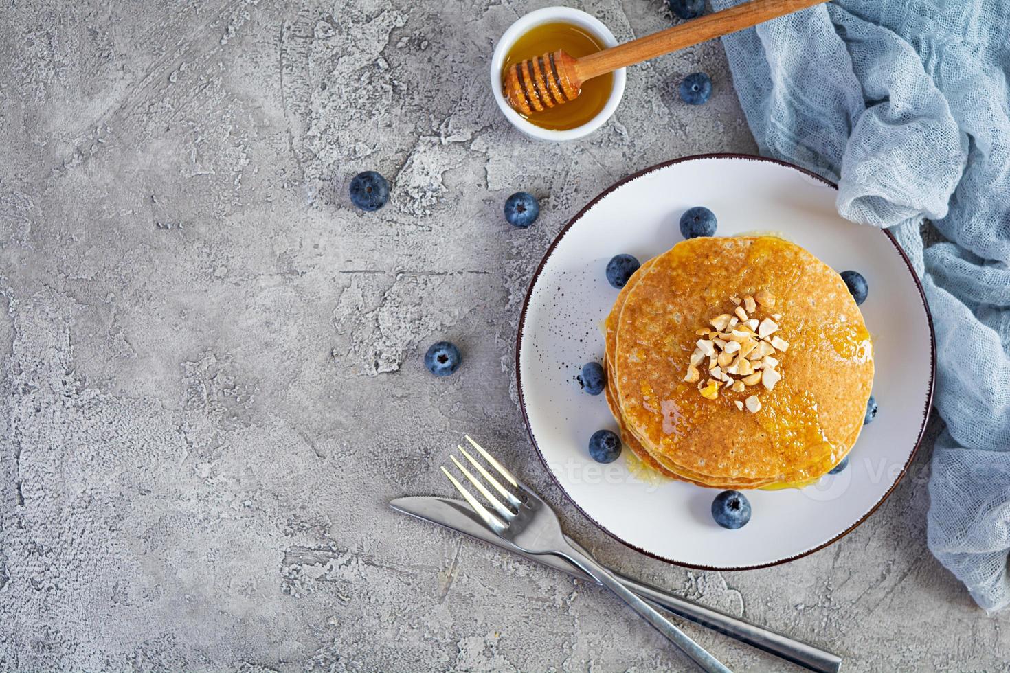 delizioso fatti in casa Pancakes con miele e mirtilli. gustoso prima colazione con crepes. superiore Visualizza foto