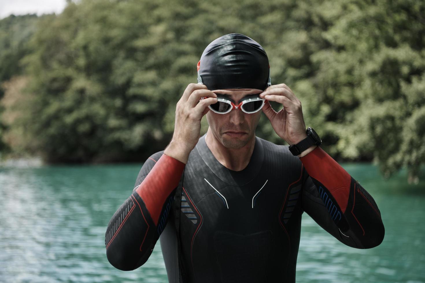 atleta di triathlon che si prepara per l'allenamento di nuoto sul lago foto