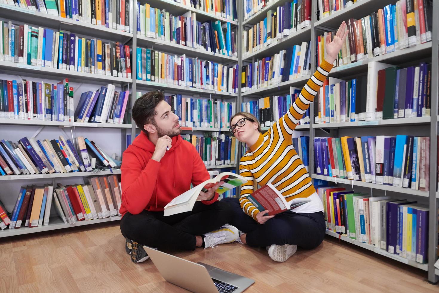 il studenti usi un' taccuino, il computer portatile e un' scuola biblioteca foto