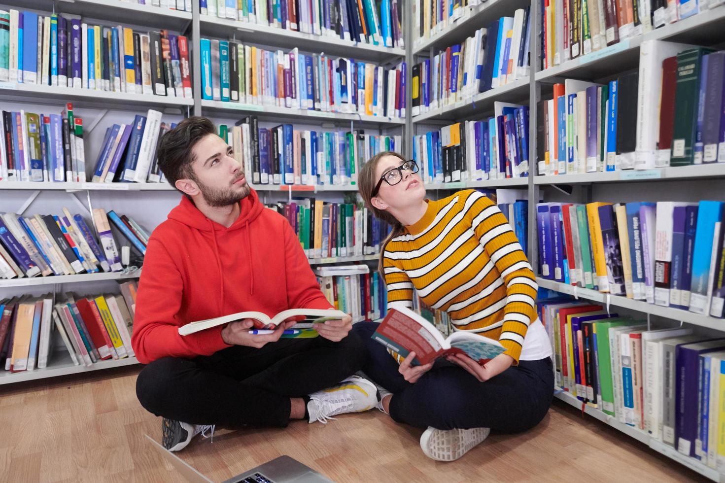 il studenti usi un' taccuino, il computer portatile e un' scuola biblioteca foto