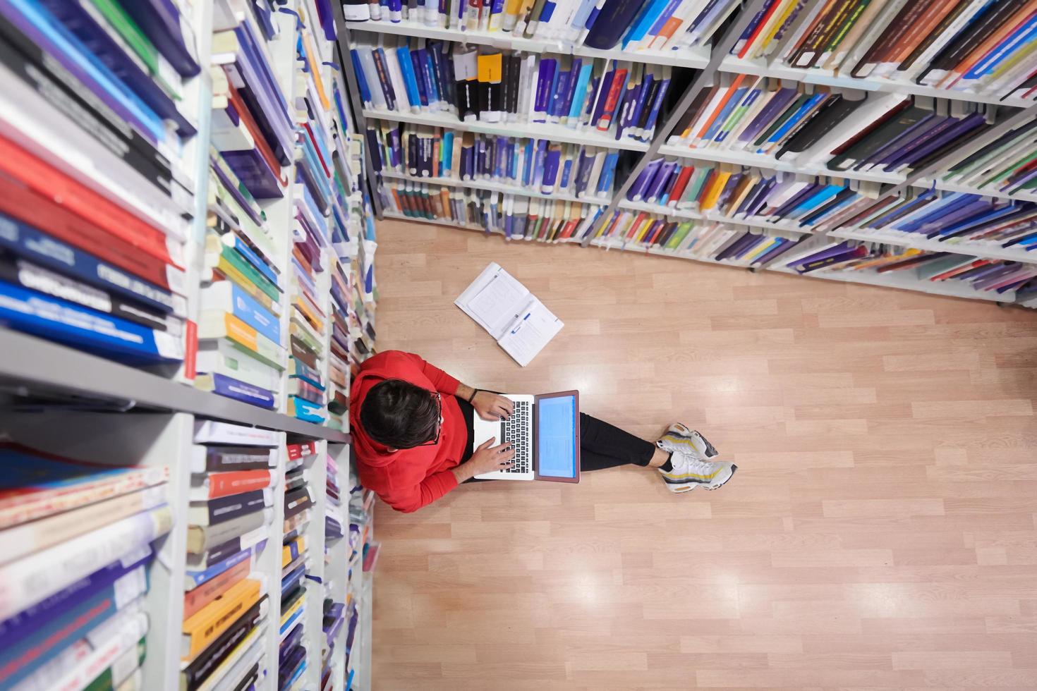 il studenti usi un' taccuino, il computer portatile e un' scuola biblioteca foto