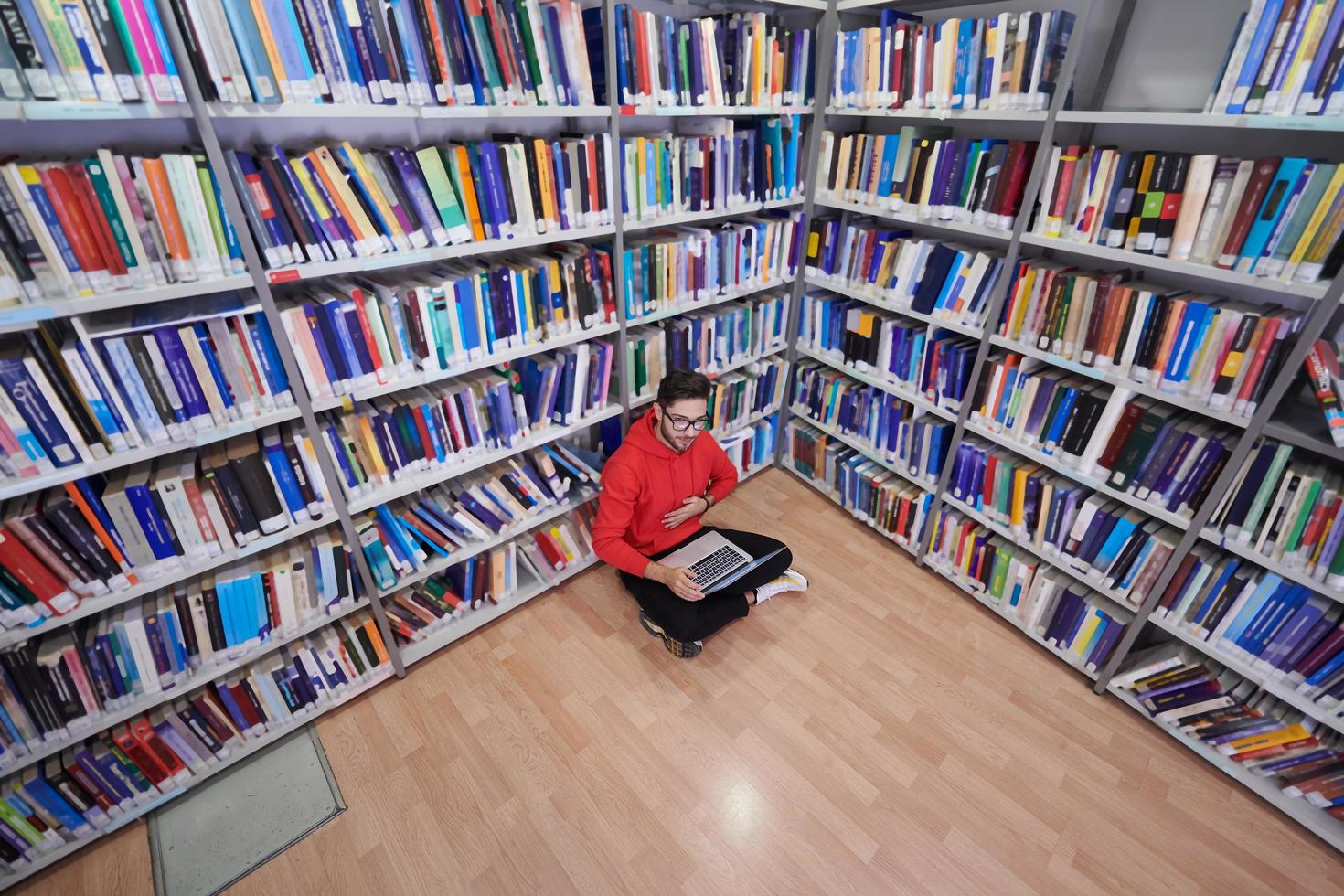 il studenti usi un' taccuino, il computer portatile e un' scuola biblioteca foto