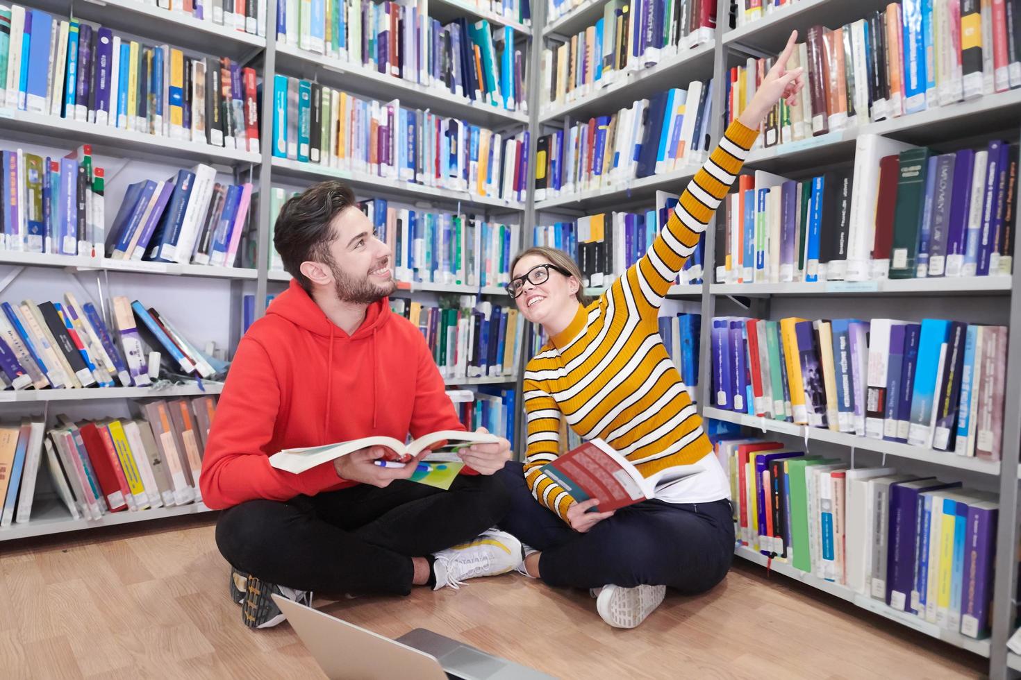 il studenti usi un' taccuino, il computer portatile e un' scuola biblioteca foto