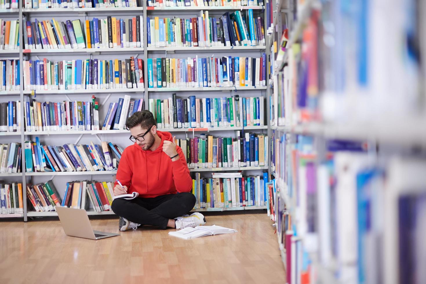 il studenti usi un' taccuino, il computer portatile e un' scuola biblioteca foto