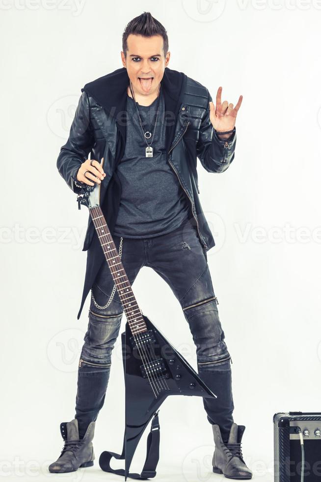 ribelle chitarra giocatore mostrando corno cartello mentre attaccare su lingua. foto