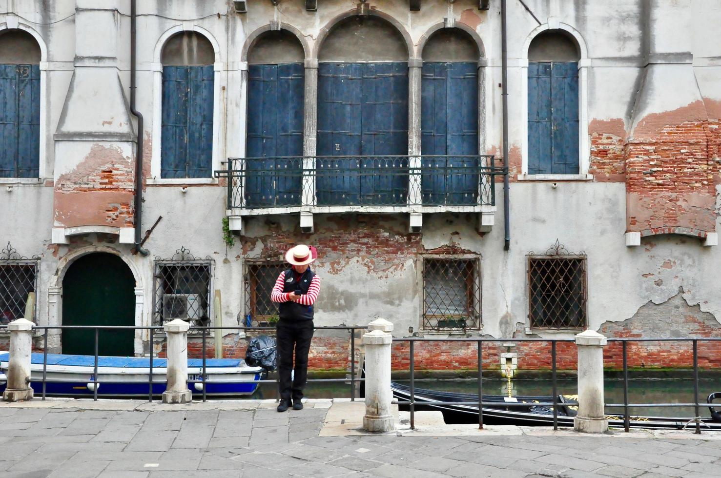 veneziano gondoliere rilassare su di gondola con il antico mattone parete su sfondo foto