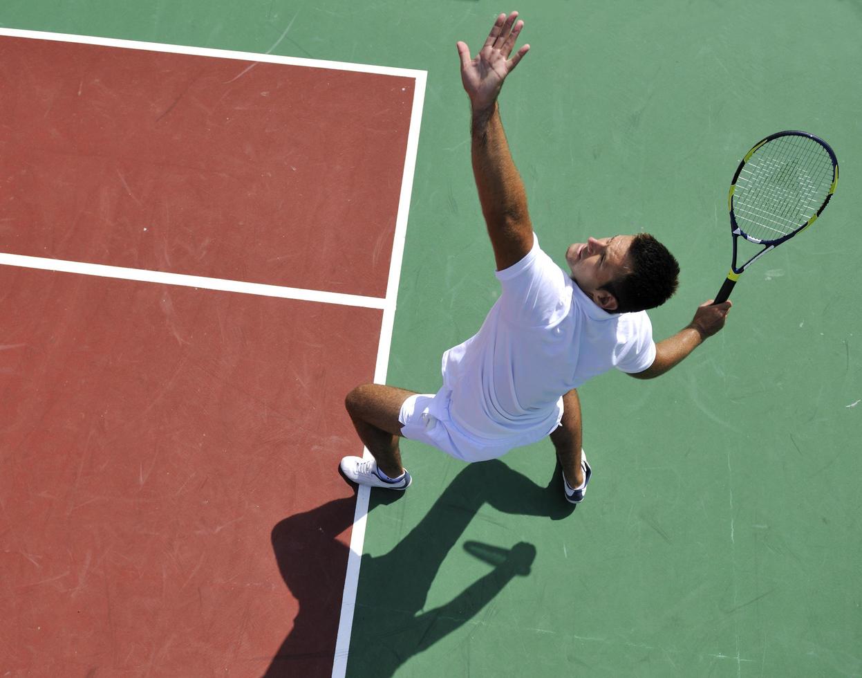 il giovane gioca a tennis all'aperto foto