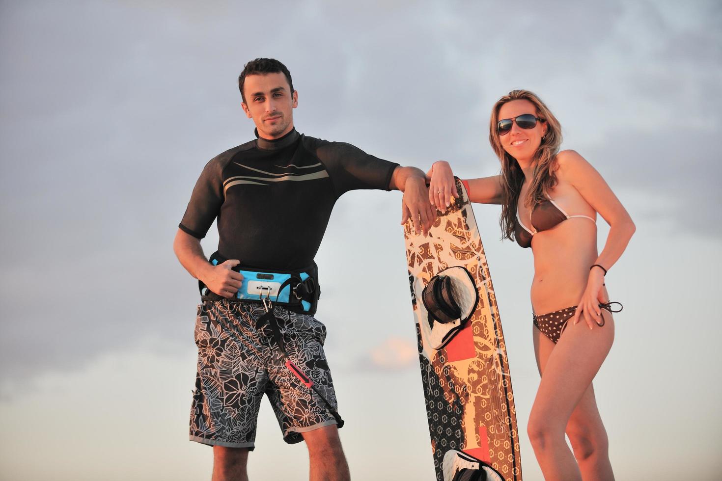 Surf coppia in posa a spiaggia su tramonto foto