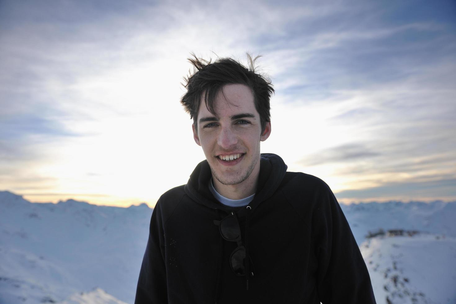 il giovane felice si diverte in inverno sulla cima della montagna foto