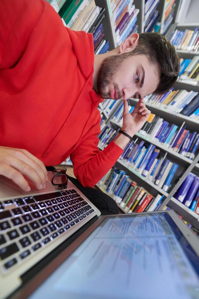 il studenti usi un' taccuino, il computer portatile e un' scuola biblioteca foto